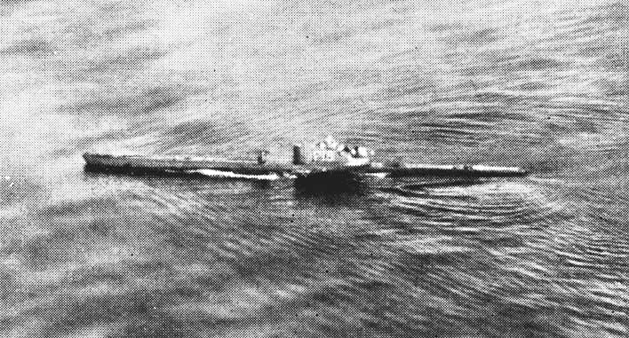 Foto de archivo en blanco y negro, tomada desde un avión, de un submarino que navega en superficie por un mar rizado, con la estela a lo largo del casco y la torreta en el centro.