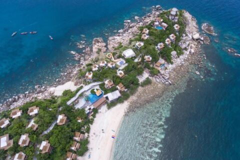 Vista aérea del Sai Daeng Resort, con sus bungalows sobre una punta rocosa, sus piscinas y su playa de arena