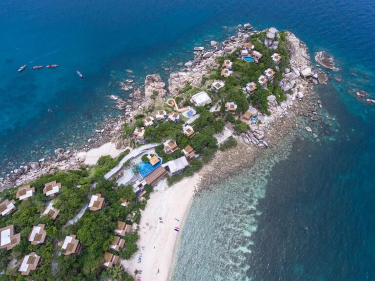 Vista aérea del Sai Daeng Resort, con sus bungalows sobre una punta rocosa, sus piscinas y su playa de arena