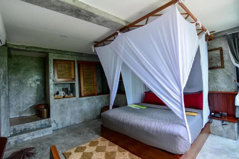 Una habitación con cama con mosquitero y un rincón para el té en un hueco de la pared