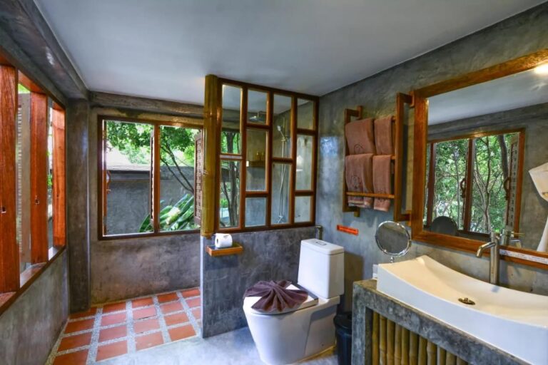 Un baño con ducha tras una mampara de cristal enmarcada en madera