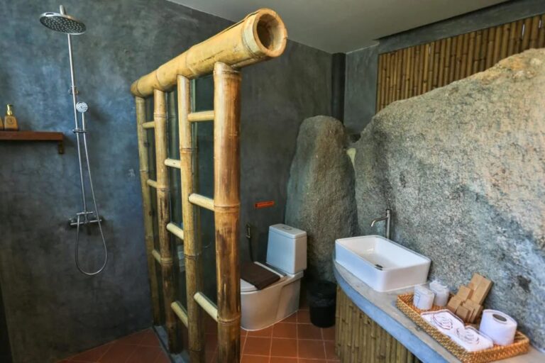 Un baño construido contra una gran roca, con ducha y lavabo