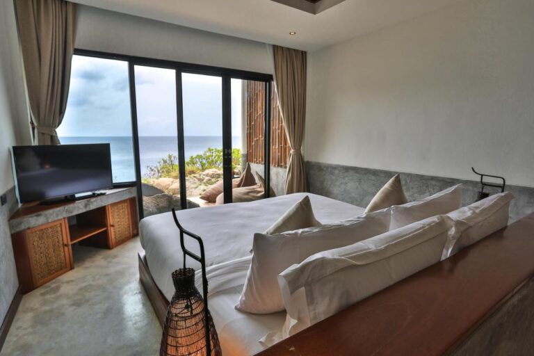 Una habitación del Sai Daeng Resort con un ventanal que da al mar y a las rocas