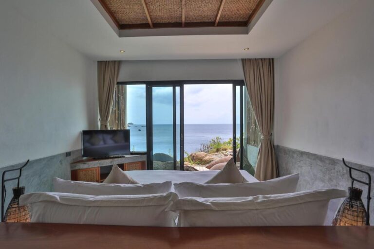 Una habitación frente al mar, vista desde la cabecera de la cama, con dos lámparas de mimbre