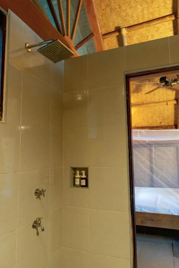 Una ducha embaldosada, abierta a la habitación y a su cama con mosquitero