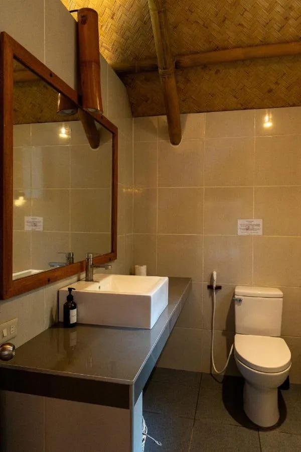 Un baño con un lavabo sobre una encimera gris, un espejo con marco de madera e inodoro