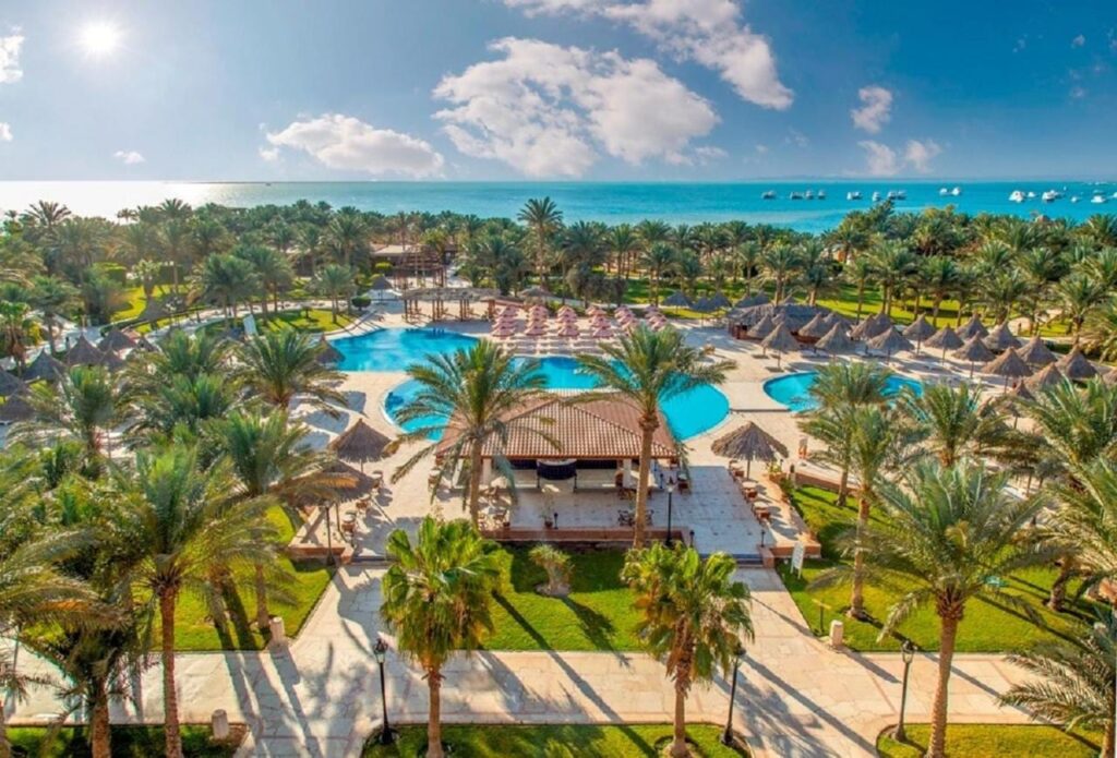 Vista aérea del Siva Grand Beach, con sus piscinas entre las palmeras y el mar Rojo con barcos fondeados
