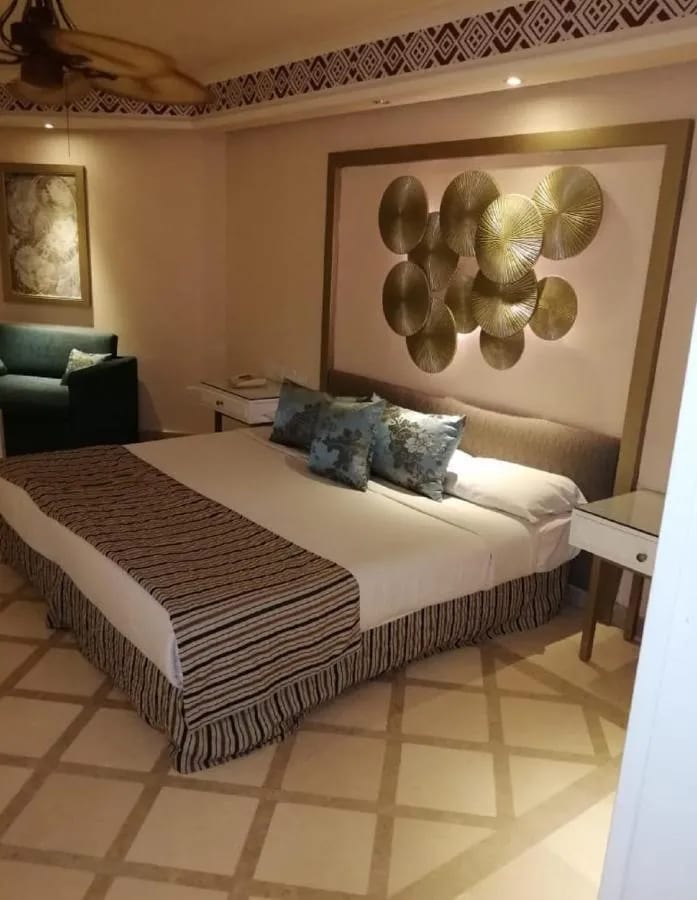 Una cama grande bajo una decoración de pared con discos dorados