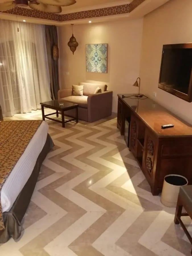 La zona de estar de una habitación, con un sofá, un escritorio de madera y suelo en espiga