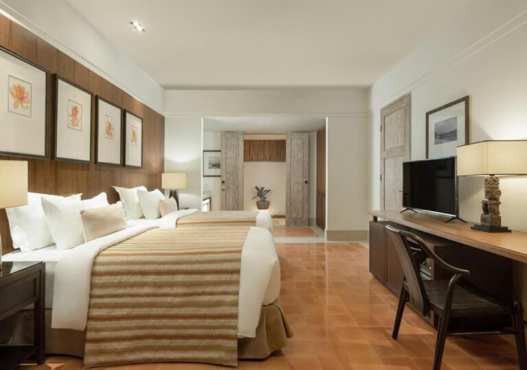 Una habitación con cama grande, un escritorio y grabados en la pared