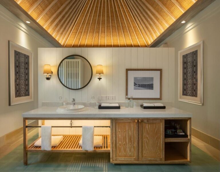Un baño con lavabo, espejo redondo y mueble de madera