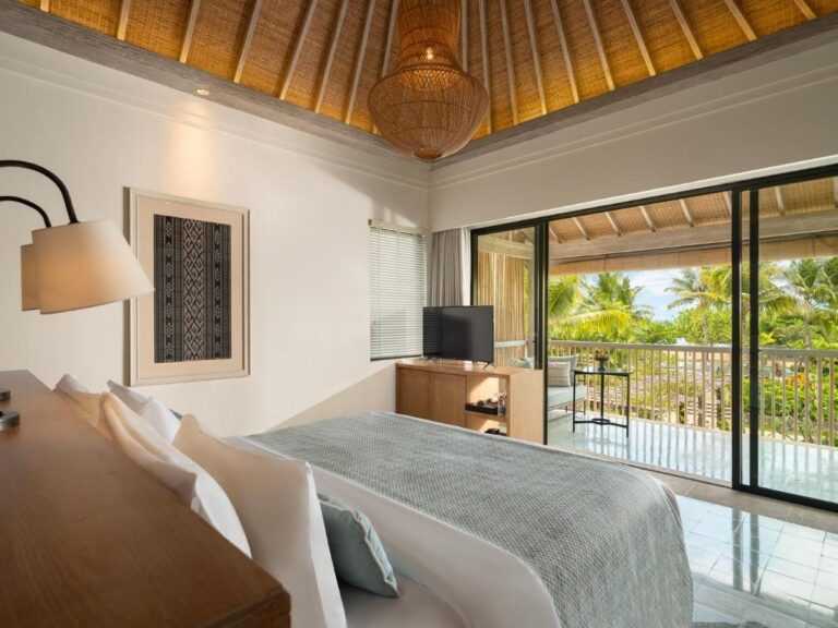 Una habitación abierta a un balcón, con vistas a las palmeras