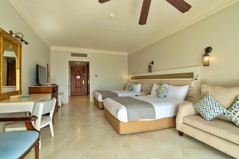 Una habitación con dos camas grandes, un sofá y un ventilador de techo