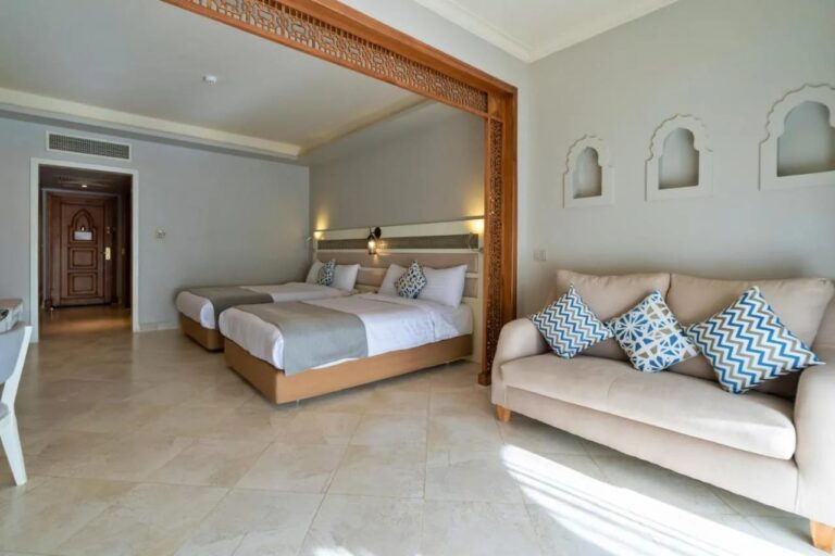 Una habitación con dos camas, un sofá y hornacinas en forma de arco en la pared