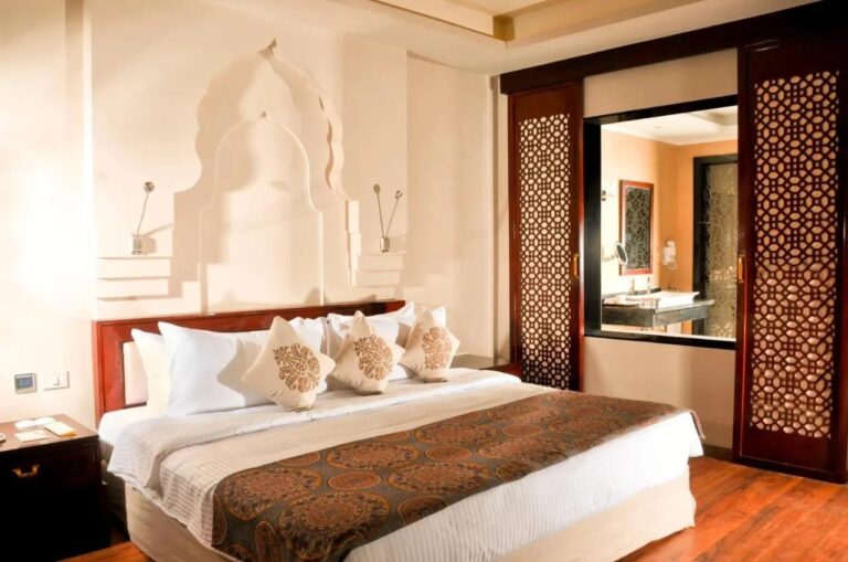 Una habitación con cama grande y paneles de madera calada abiertos al baño
