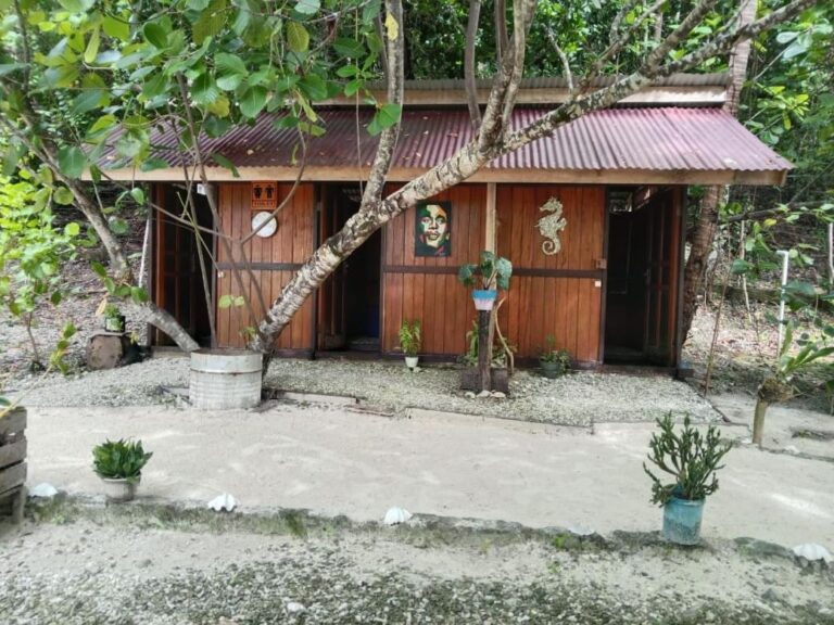 La caseta de madera de los baños, bajo los árboles, con un caballito de mar decorativo
