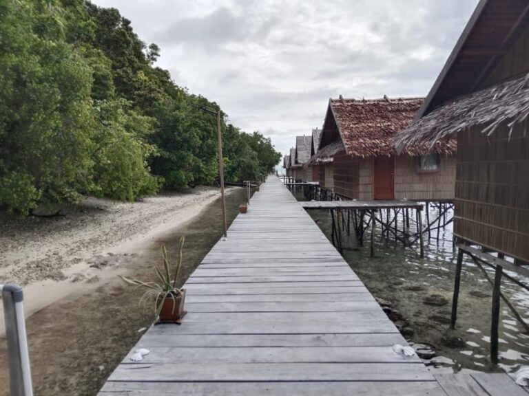 Una pasarela de madera entre la playa y los bungalows sobre pilotes